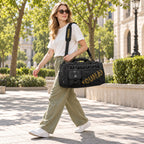 Woman carrying the Black travel duffel with its removable shoulder strap in a sunny park