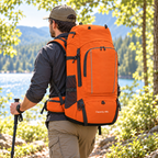 Hiker wearing the Orange 80L backpack in a rear three-quarter view beside a sunlit woodland lake