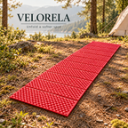 Red foil-backed folding foam camping mat fully unfolded at a lakeside campsite