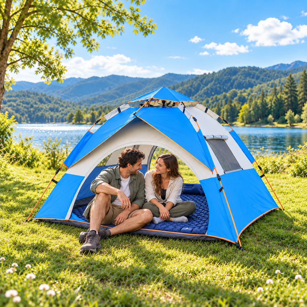 Two adults seated together inside a Sky Blue and Off-White tent on a blue camping pad at a bright lakeside campsite; pad sold separately