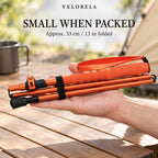 The orange five-section trekking pole folded and held across an adult hand